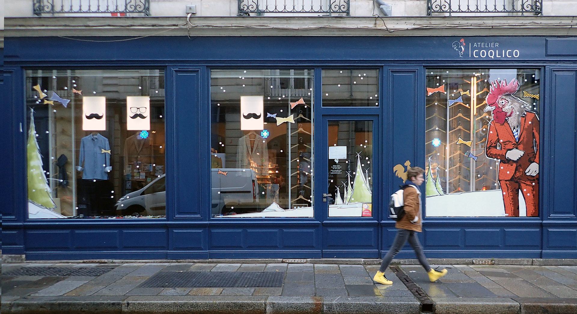 Décor de Noël peint sur la vitrine d’Atelier Coqlico avec coq élégant et sapins stylisés