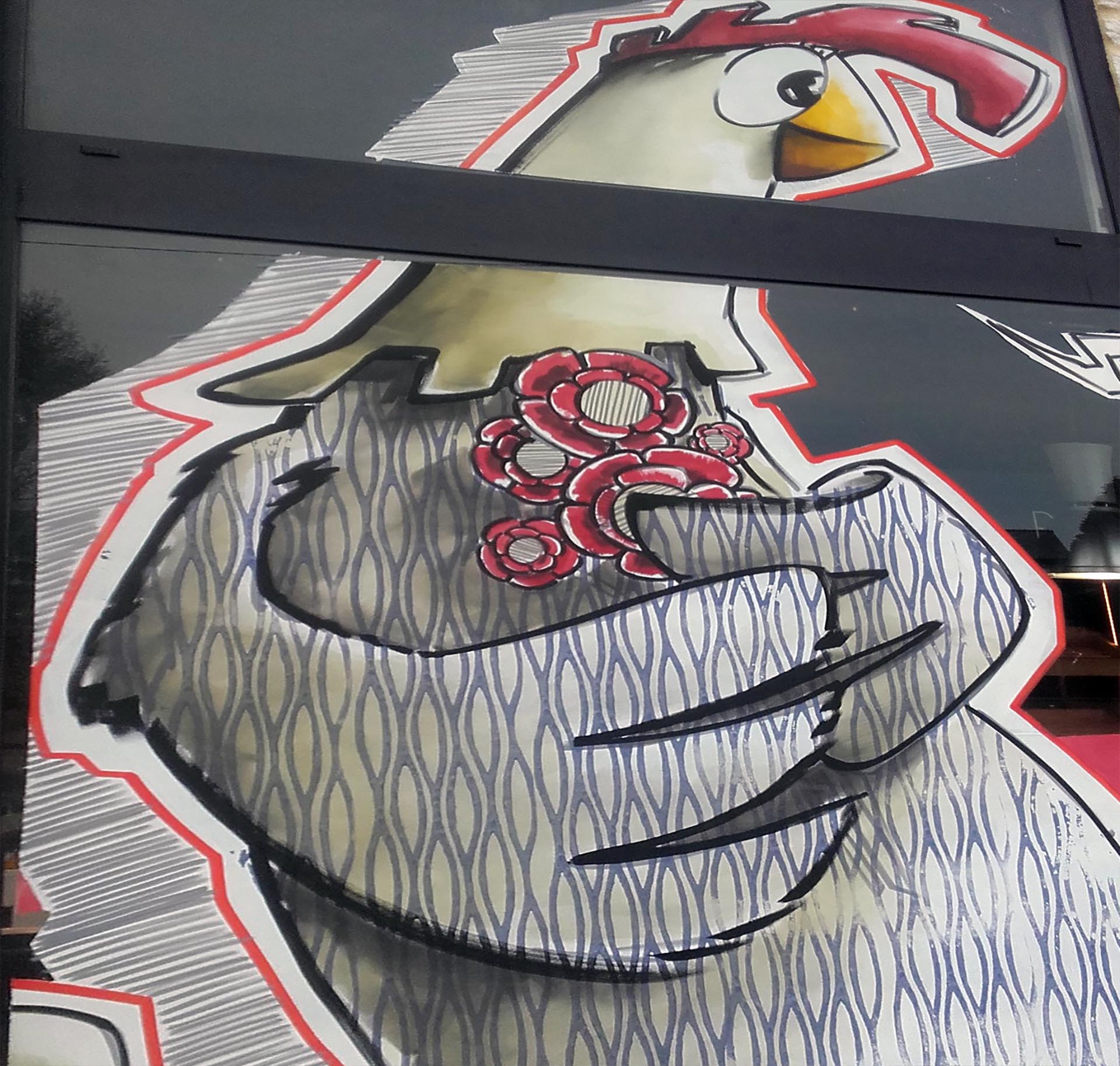 Peinture sur vitrine de Pâques par Jean‑Charles Varlet, poule stylisée et fleurs rouges.